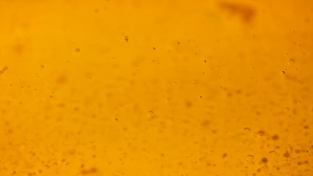 Golden oil bubbles float through an amber liquid in a glowing macro. Concept food branding, cosmetic packaging, banners, websites and abstract advertising.