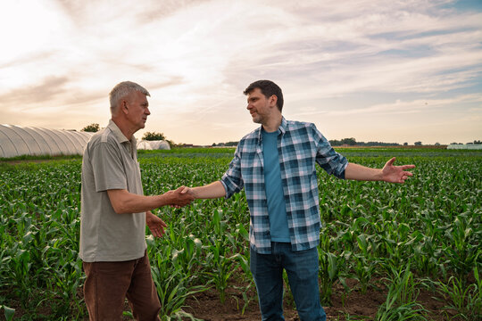 Two farmers on a field having an agreement shaking hands and talking 