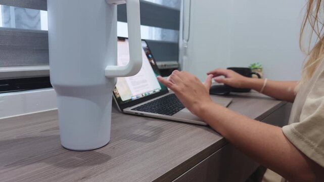 Woman's hands typing on a laptop keyboard, using technology for remote work and digital communication from a modern home office desk, emphasizing productivity and flexible working