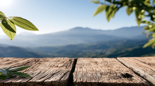 Rustic wooden table with green leaves in foreground against a misty mountain landscape backdrop