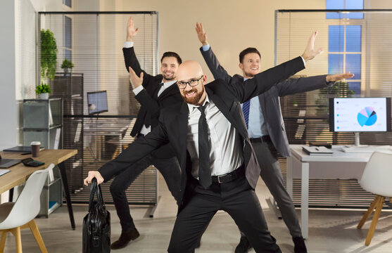 Businessmen team dancing in office celebration success. Three colleagues pose playfully, enjoying a joyful victory and fun among desks and screens. Concept of joyful corporate celebration.