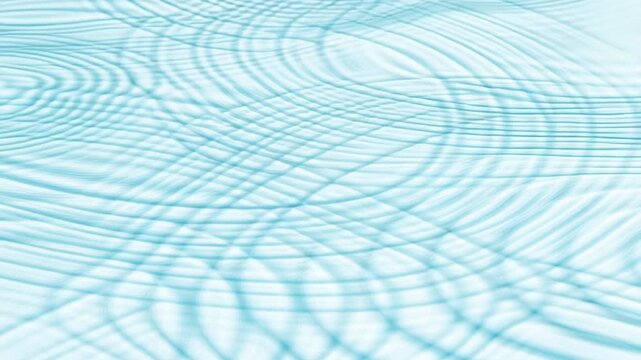 Slow motion tracking shot of ripple patterns shifting and intersecting across shallow water surface in studio pool with soft cyan lighting