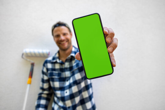 Handyman online booking service. Man showing smartphone with green screen. Home repair services
