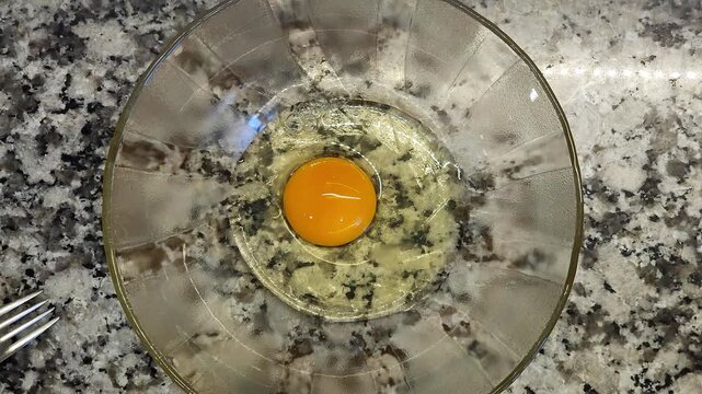 Manos rompiendo huevos crudos dentro de un cuenco transparente