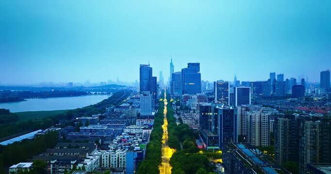 Nanjing skyline and illuminated central avenue beside Xuanwu Lake, Jiangsu, China, viewed in evening light, showcasing dense urban development and waterfront infrastructure.