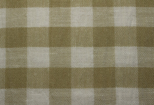 Texture of crumpled ocher gingham fabric background. Close up of wrinkled gold and white plaid linen like cloth.