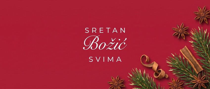 Sretan Bozic Croatian Merry Christmas background with pine branches, star anise spices, copy space, festive holiday banner for winter season greeting, decorative flat lay composition on red backdrop