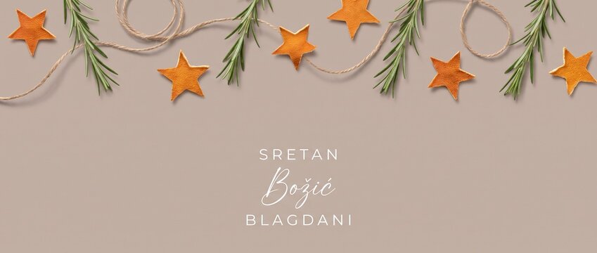 Christmas background flat lay banner with orange peel stars and rosemary sprigs for Croatian holiday greeting card message reading Sretan Bozic Blagdani on minimalist beige backdrop with copy space.