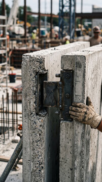 Construction worker installing heavy precast concrete wall panel on site