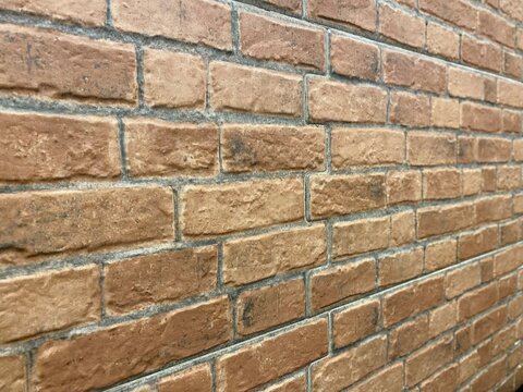 Full frame view of a brown weathered brick wall texture with grey mortar joints
