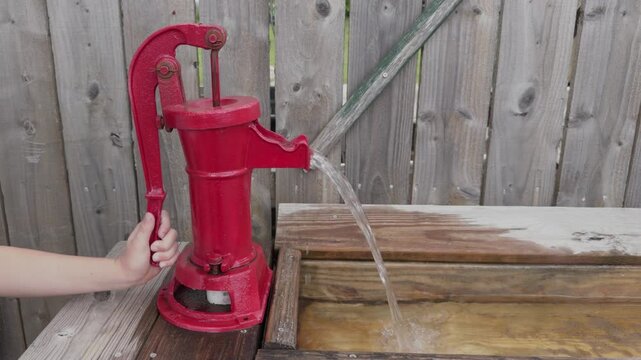 Red water hand pump pumping water