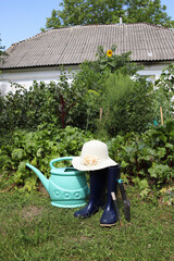 Rubber boots and a large garden watering can stand on a green lawn. © Наталья Николаева