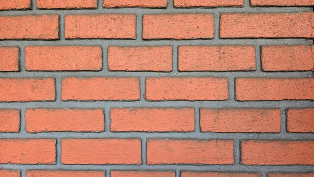 Repeating red brick wall texture with visible gray cement plaster lines between the bricks, creating a repeating masonry pattern suitable for architectural backgrounds, construction designs, and digit