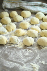 Fototapeta premium Preparation of homemade yeast dumplings on a rustic wooden table, filled yeast dumplings ready for cooking, traditional Czech cuisine, homemade cooking, dough preparation