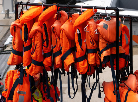 Orange Life Jackets Hanging on Rack at Marina