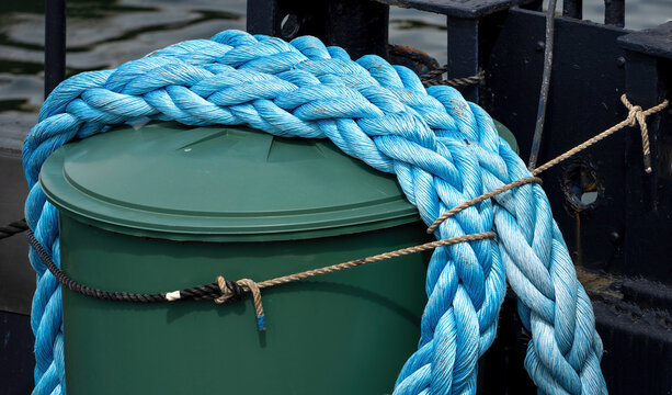 Thick Blue Mooring Rope Coiled on Harbor Bollard