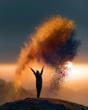Woman silhouette throwing colorful powder in sunset light