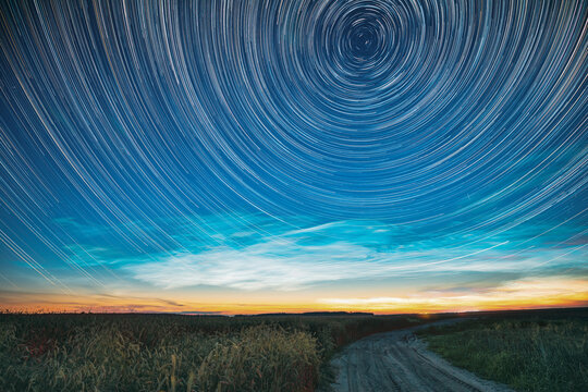 Morning Sunrise In Countryside. Unusual Amazing Effect Of Cloud And Stars Trails Above Countryside Rural Field Landscape With Young Green Wheat Sprouts In Springtime. Soft Colors