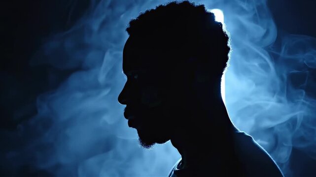 African american man in profile illuminated by backlighting. Silhouette with blue atmospheric smoke. Moody portrait concept for artistic creative visual storytelling.