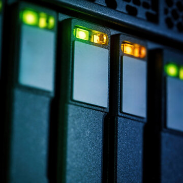 Server rack with blinking green and amber indicator lights. Close up view of storage drives shows system activity and status in data center. Digital technology hardware.