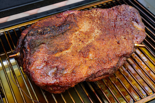 Brisket BBQ on a grill cooking low and slow in an outdoor setting during a sunny afternoon