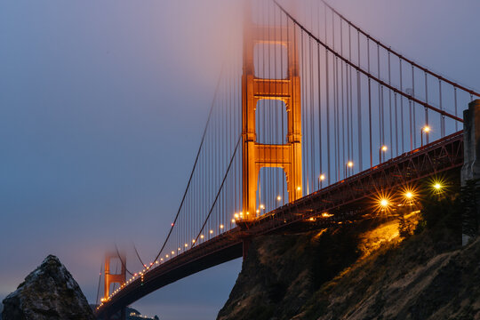 Illuminated Golden Gate Bridge tower in San Francisco Bay fog seen from Fort Baker