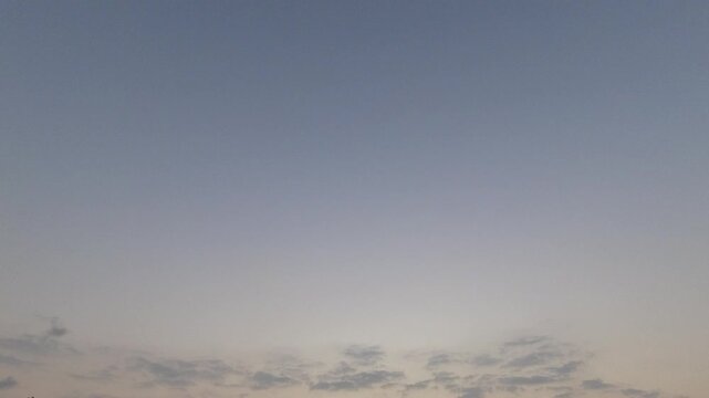 Time-lapse of a calm blue-grey sky with small clouds at the bottom. Ample negative space for text and graphic overlays. Peaceful nature background.