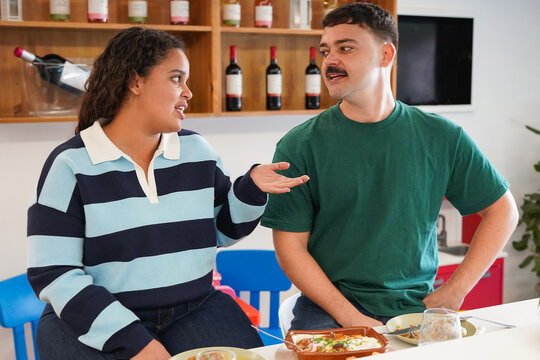 Happy young multiracial friends eating lunch together inside modern restaurant - People, lifestyle and food concept
