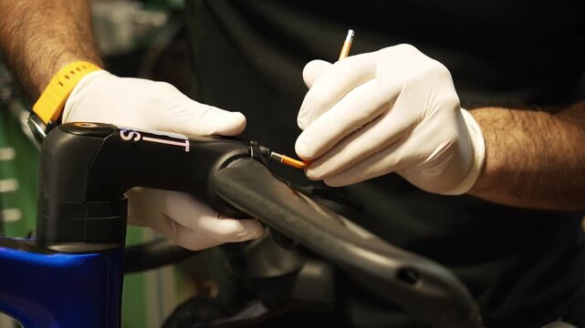 Bike mechanic wearing protective gloves loosens handlebar bolts during bicycle repair. Professional bike maintenance and technical service concept