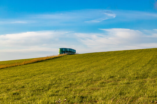 Hirtshals, Denmark Green plastic-covered hay bales on a hillside on a windy day.