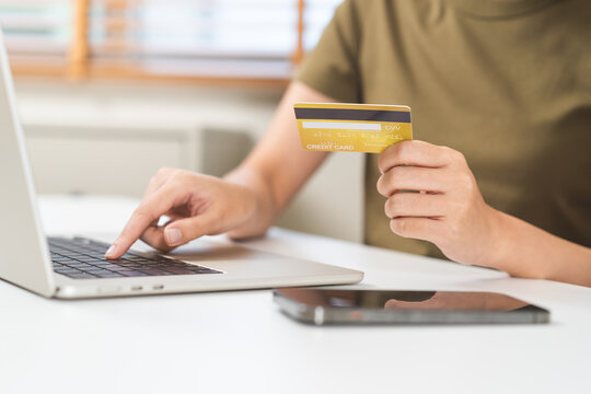 Close up of woman hand holding credit card and typing on a laptop computer keyboard for online shopping payment, secure digital banking and e-commerce retail transaction concept.