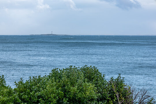 Blick &uuml;ber den Ozean auf den schwarz-wei&szlig; gestreiften Dog Island Leuchtturm in der Foveaux-Stra&szlig;e bei Bluff, Neuseeland