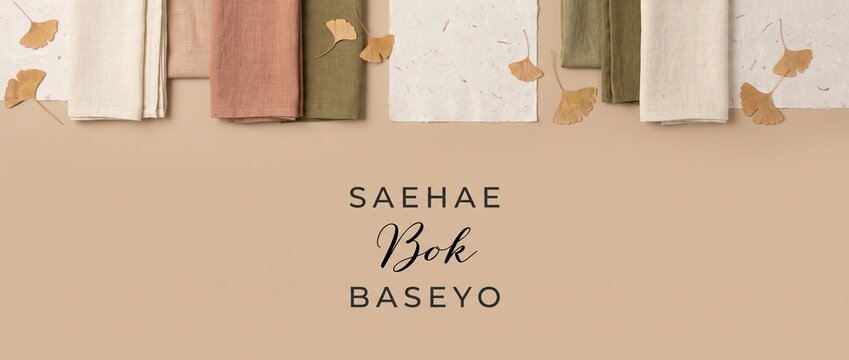 Korean New Year Seollal flat lay with linen fabric napkins and dried ginkgo leaves on beige background featuring Korean greeting typography for autumn minimalist festive banner design header backgroun