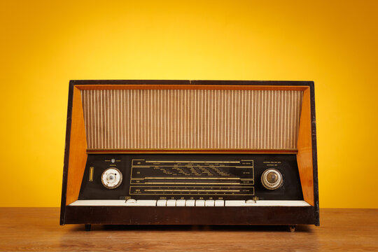 Vintage Retro Wooden Radio Receiver on Table against Yellow Background. Nostalgic Analog Music Player and Home Decor