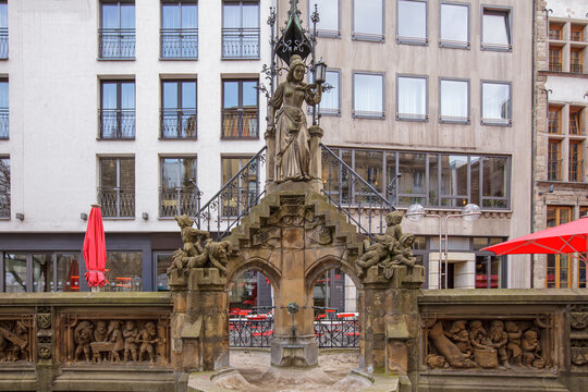 Historic Heinzelmannchen Fountain with Ornate Gothic Statue in European Old Town Square, Cologne Germany. Detailed Stone Carvings of Gnomes and Local Folklore Legends