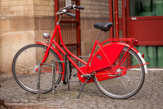 Red Vintage City Bicycle Parked on Cobblestone Street. Urban Eco-Friendly Sustainable Transportation. Vintage Style Urban Cycling Transportation