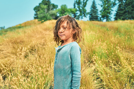 Close-up portrait of a boy with wet messy hair on a golden hillside