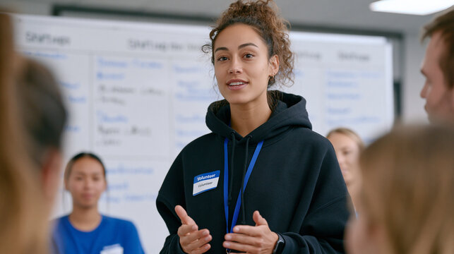 Volunteer coordinator standing at a whiteboard covered in shift schedules and volunteer names, briefing a group of new recruits in a nonprofit training room, program management,
