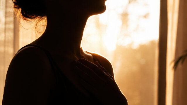 Silhouette woman hand neck sunlight healing somatic relaxation calm peaceful indoor warm backlight meditation wellness selfcare female body skin