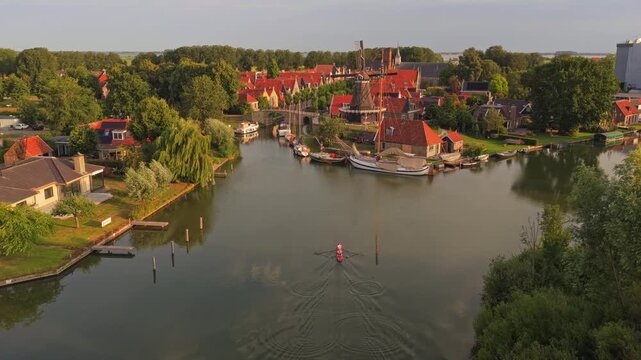 Rower paddling a scull boat on a canal in sloten, friesland at sunrise