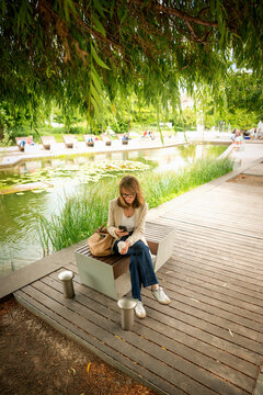 Confident mid-aged woman sitting in a city park and using a smartphone