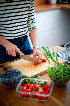 A middle-aged blonde woman standing in the kitchen and preparing organic salad