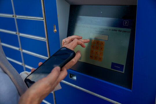 Close-up of a woman's hand touching the parcel locker touch screen