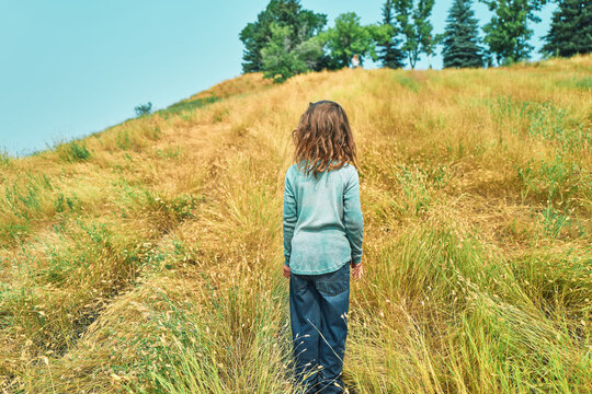 Boy walking up a grassy hillside path from behind