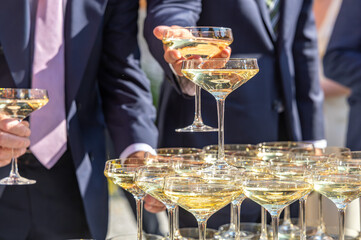 Guests take glasses from a champagne tower at an outdoor wedding reception. © Christo