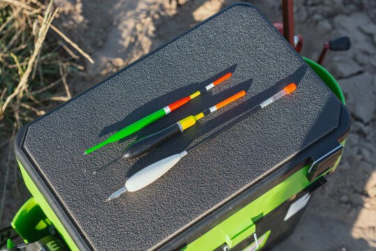 Fishing floats and tackle accessories arranged on a tackle box outdoors near water. Angling equipment concept for fishing brands, sports retail, hobby products, recreation and outdoor lifestyle.