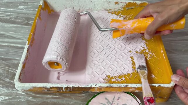 Preparing to paint the walls of the house. Roller and paint tray. A person's hand rolls a paint roller
