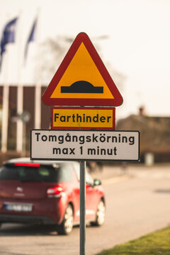 Swedish road warning sign for speed bump and idling restriction on urban street.