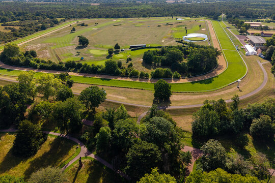 Aerial view of Magdeburg hippodrome and golf course shows oval racetrack, fairways, ponds and surrounding woodland. Summer landscape combines sport, recreation, greenery and open parkland