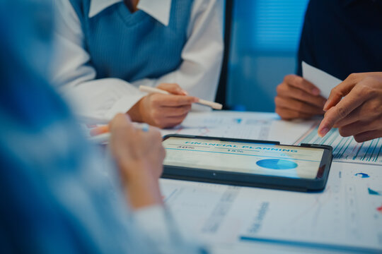 Close up asia businesspeople meeting plan analysis statistics brainstorm and tablet point graph chart employee take note in office conference room at night. Business finance partners strategy success.